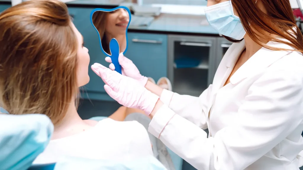 A patient checking her smile in a hand mirror after a checkup